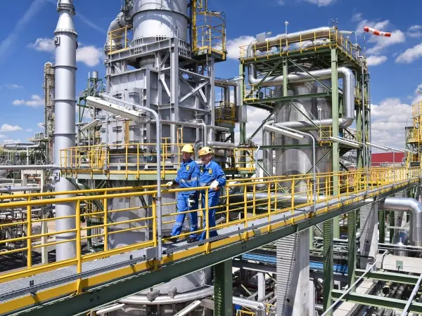 A chemical plant field installation showing large steel pipes and fittings interconnected across platforms and supports.