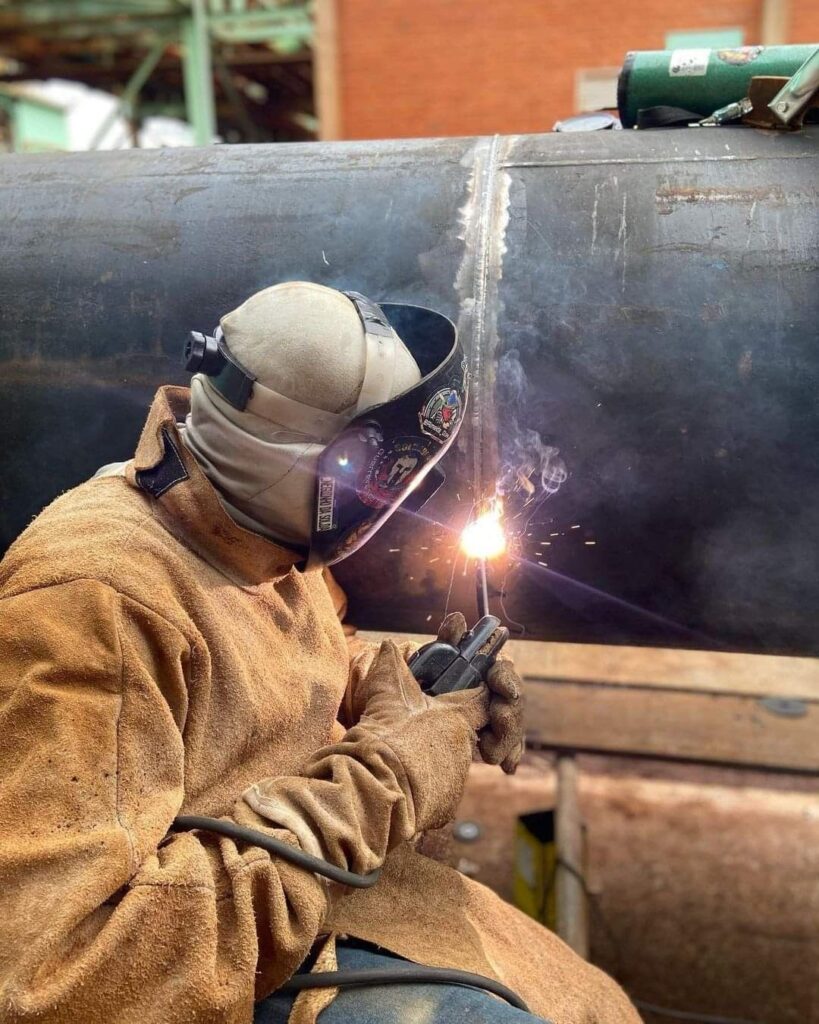 Technician welding a pipe elbow on a steel pipeline