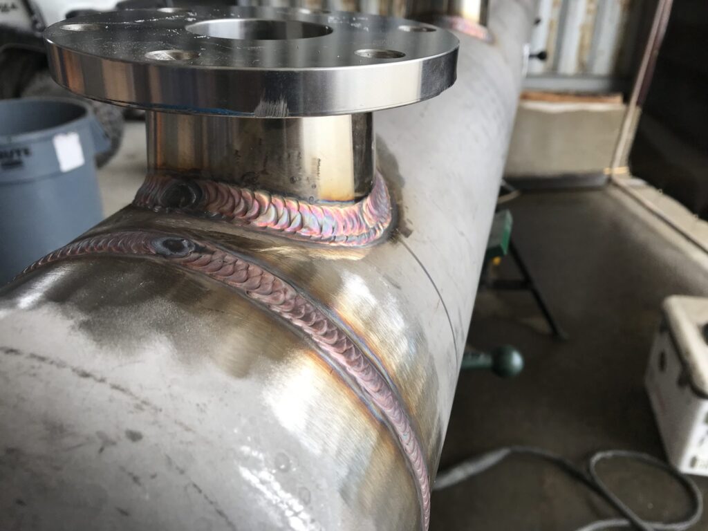 Technician welding a pipe joint on industrial pipeline