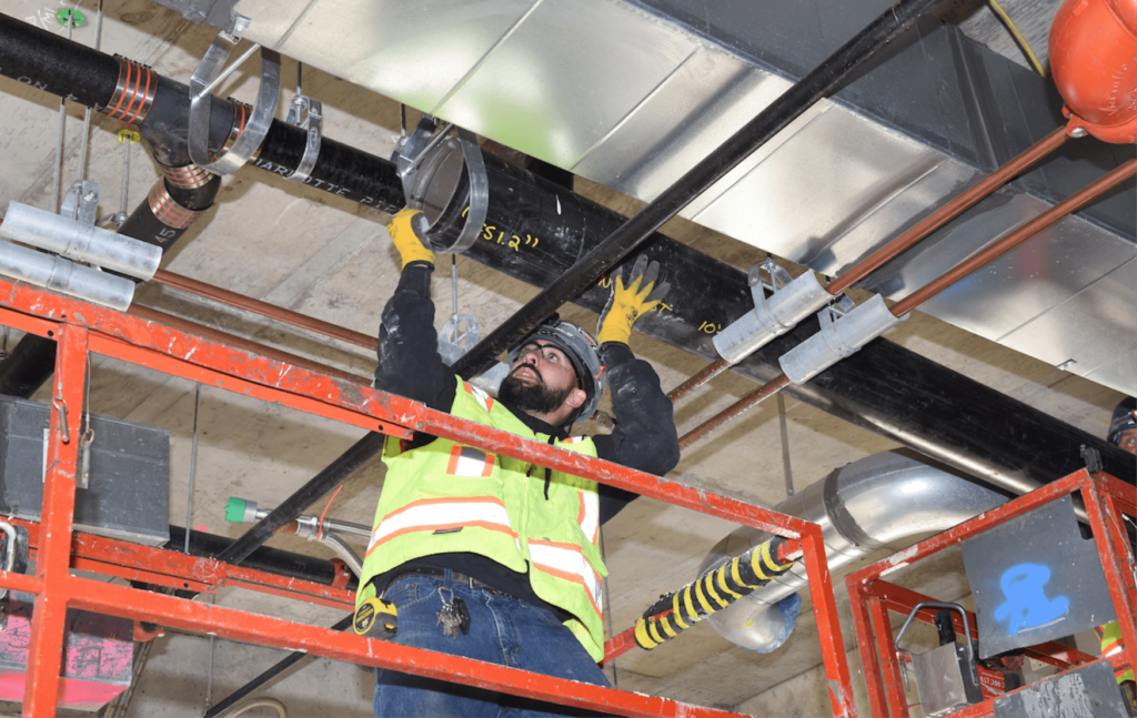 Technician installing a coupling sprinkler line in a building.
